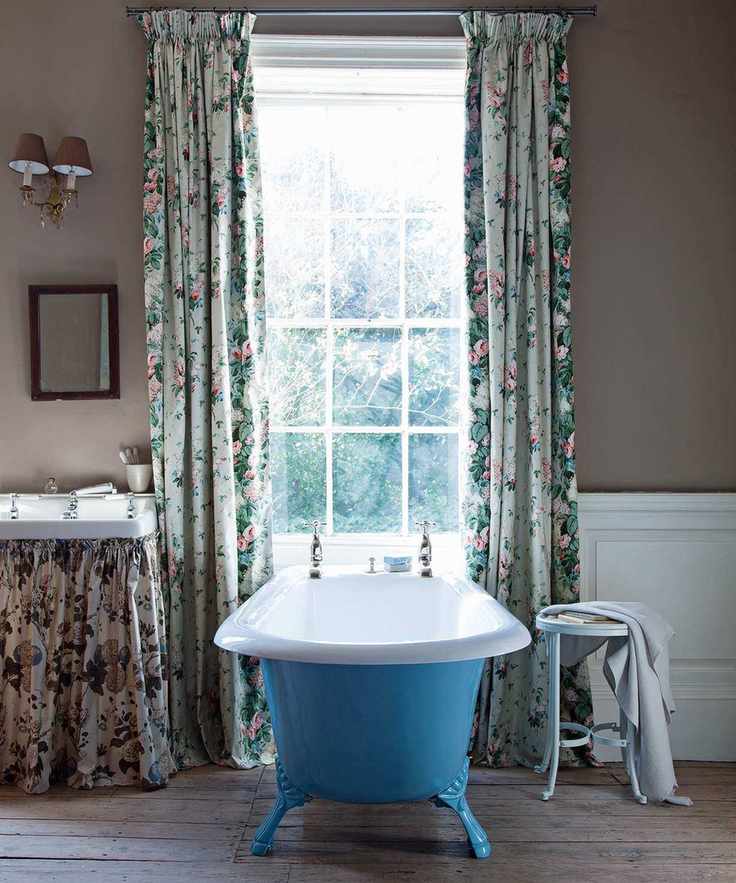 Bathroom with roll top bath with blue exterior, floral patterned curtains and floral curtain on vanity