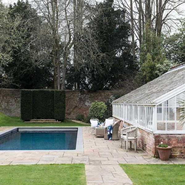 An example of pool landscaping ideas showing a traditional garden room with glass panels