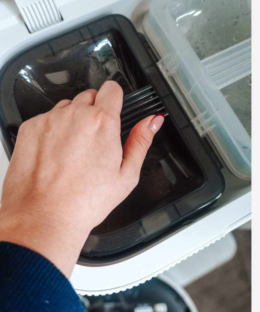 A hand holding the water tank handle of the Dreame X50 Ultra robot vacuum base station