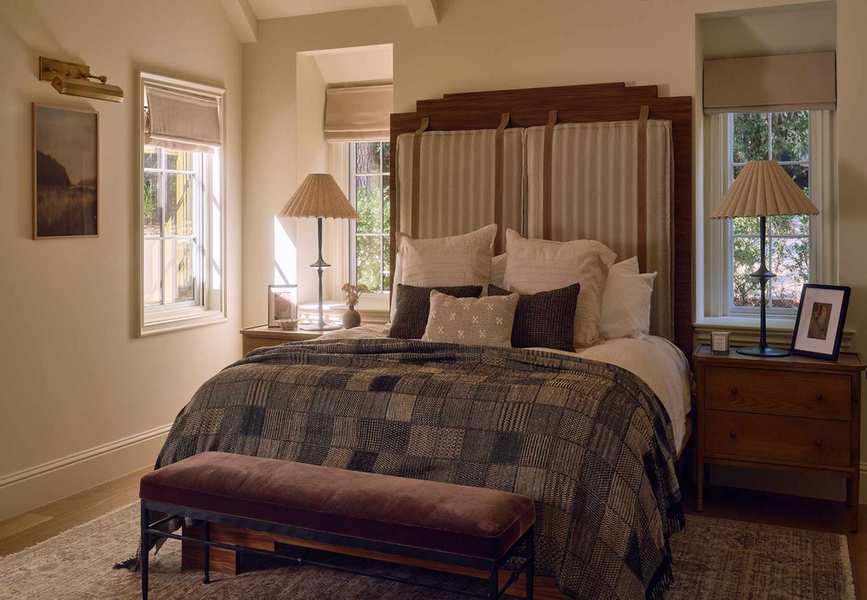 a large primary bedroom suite with a tall wooden and upholstered bed with patchwork quilt