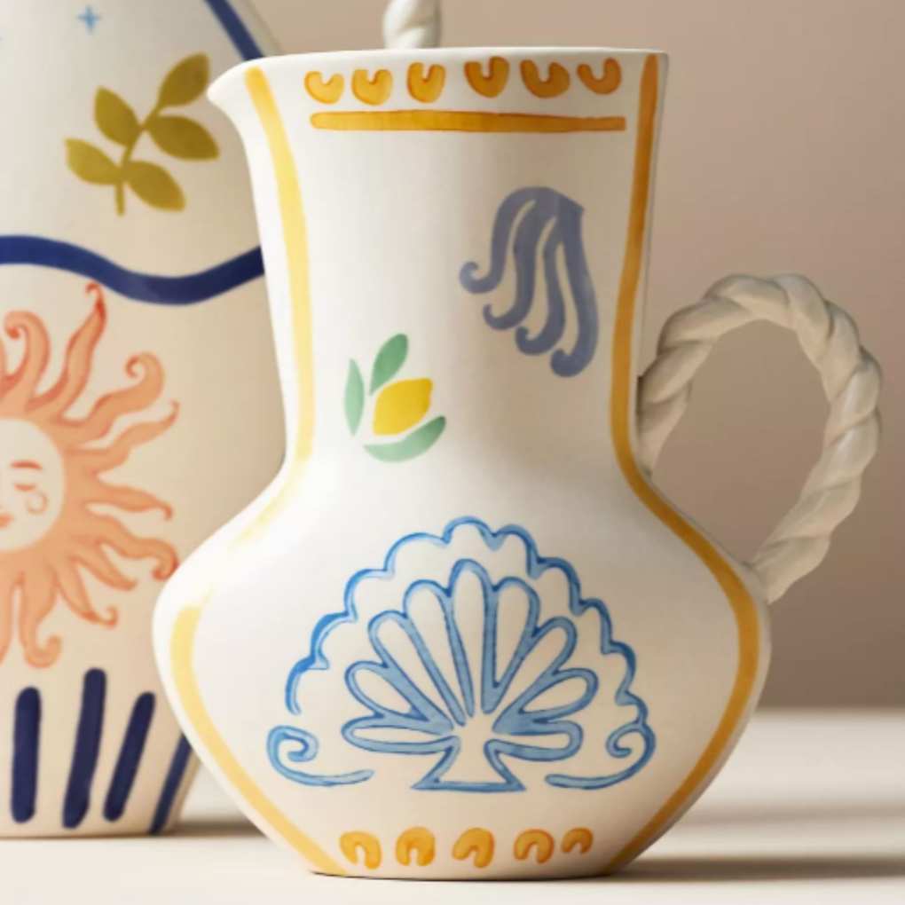 white vase with blue and yellow painted pattern and braided handle