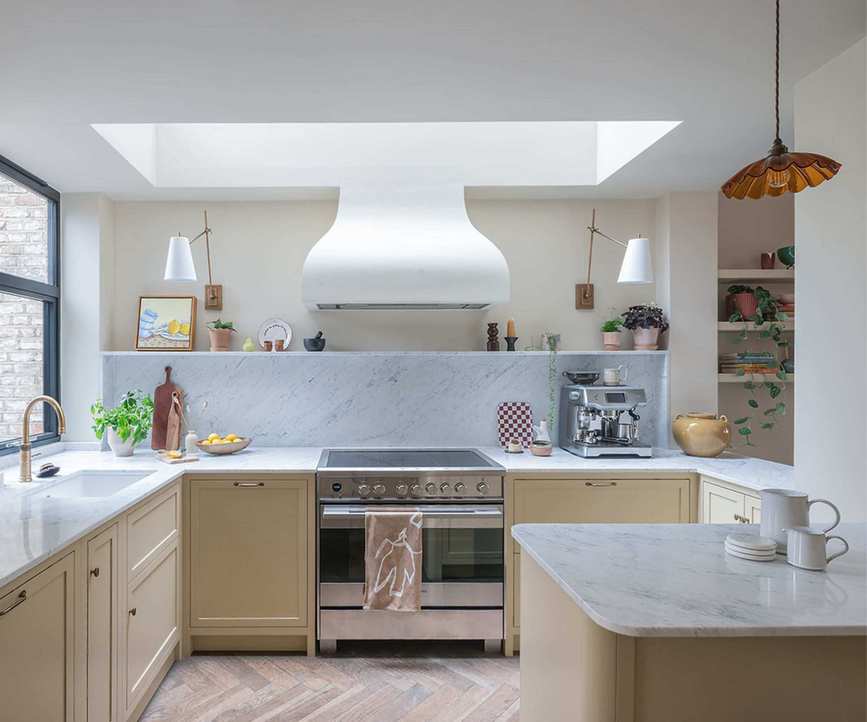 A small U-shaped kitchen with a peninsula island, beige cabinets, cream walls, and marble countertops