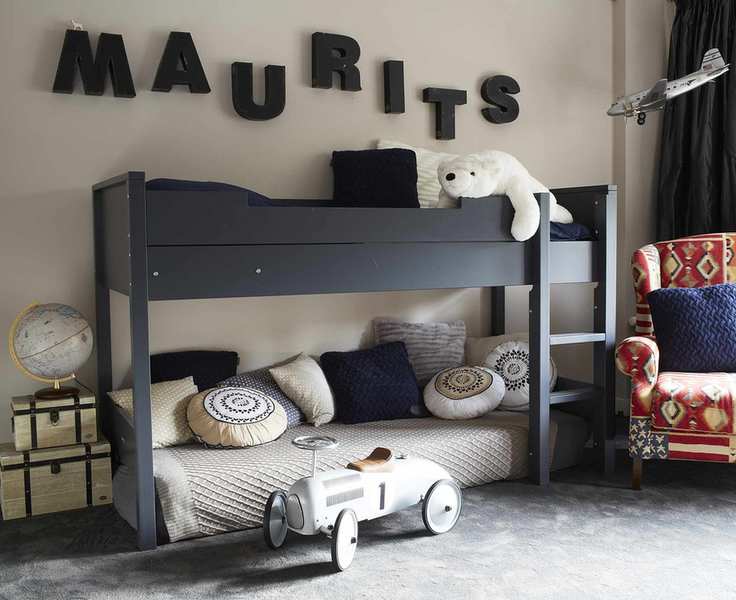 A black loft bed with the lower section styled as a daybed in a neutral room