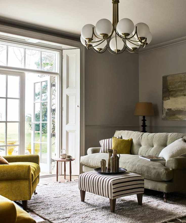 sage green painted living room with neutral sofa and ceiling light with open white French doors opening into terraced patio