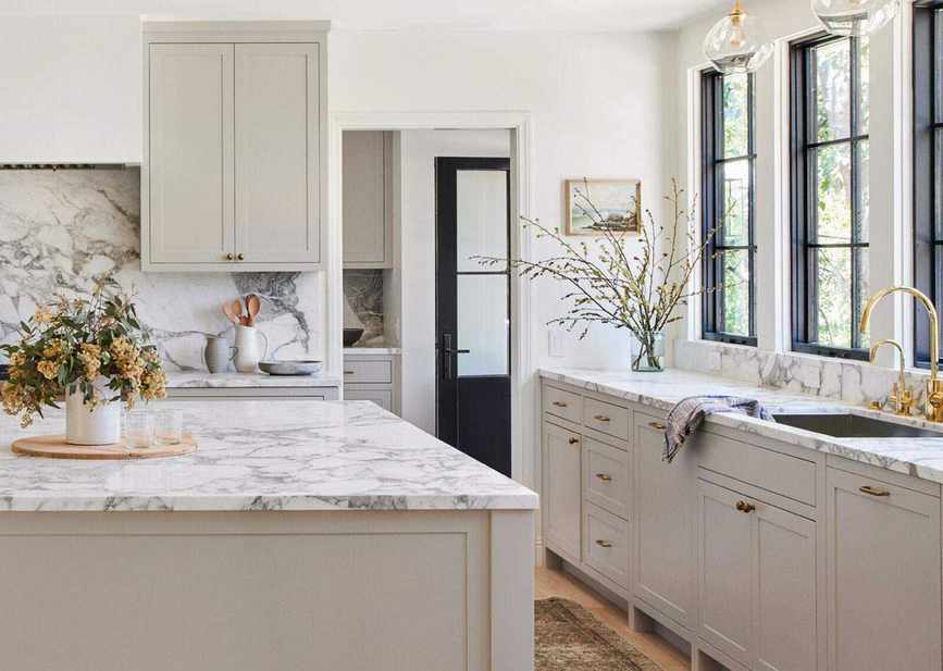 An example of how much does it cost to have kitchen cabinets painted showing a large kitchen with cream cabinets and a marble worktop