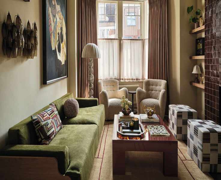 a Victorian style living room with bay window with two sheepskin chairs, a burgundy tile fireplace, green sofa and a wooden coffee table
