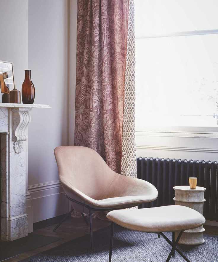 A cozy living room with pale pink walls and a marble mantelpiece.