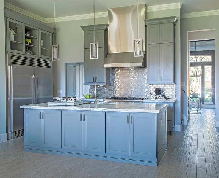 Metallic wall tiles in kitchen with blue cabinets