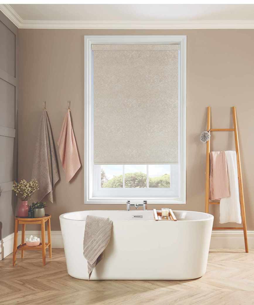 Freestanding white bathtub on wooden floor with neutral roller blinds