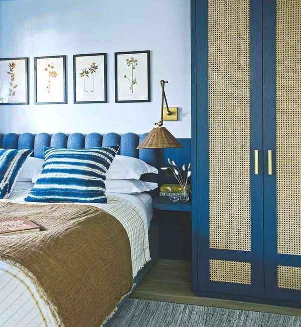 Stylish blue bedroom featuring a large bed and botanical prints on the wall.