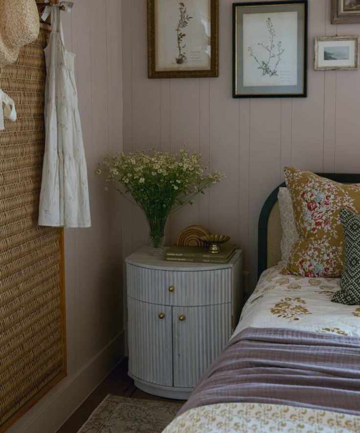 bedroom with floral bedding, a wooden ribbed bedside table, and a gallery wall of floral pictures