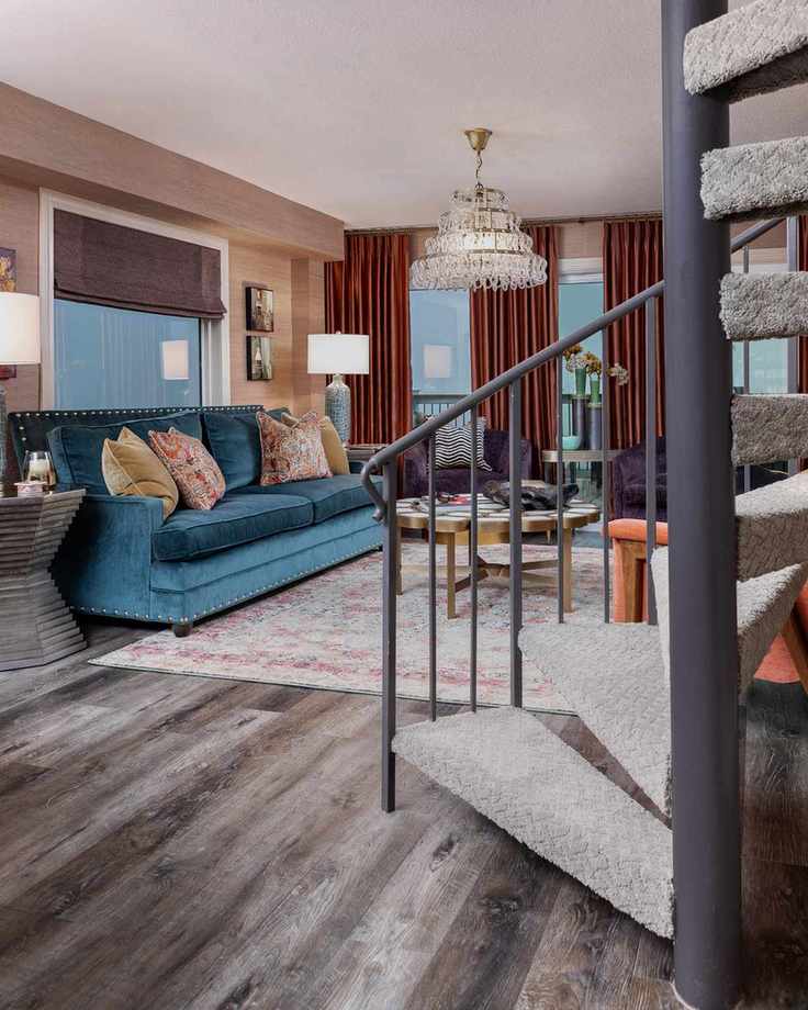 Living room with blue sofa and chandelier and spiral staircase