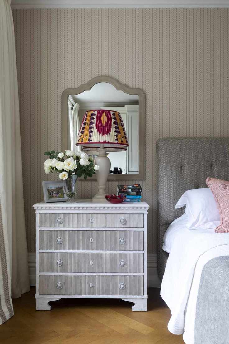 bedroom with stone and blue wallpaper, grey upholstered bed, vintage bedside, patterned lampshade, wooden floor