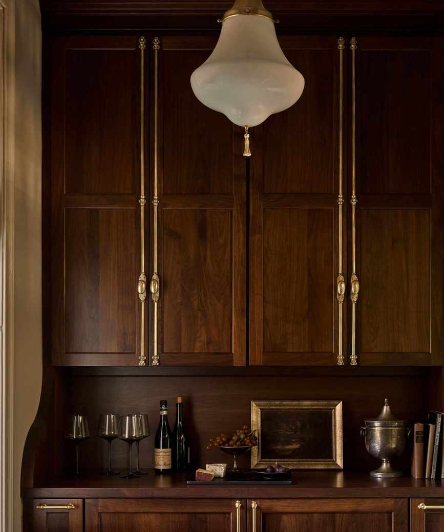 Bar pantry with dark wood cabinetry, gold hardware, and antique decor