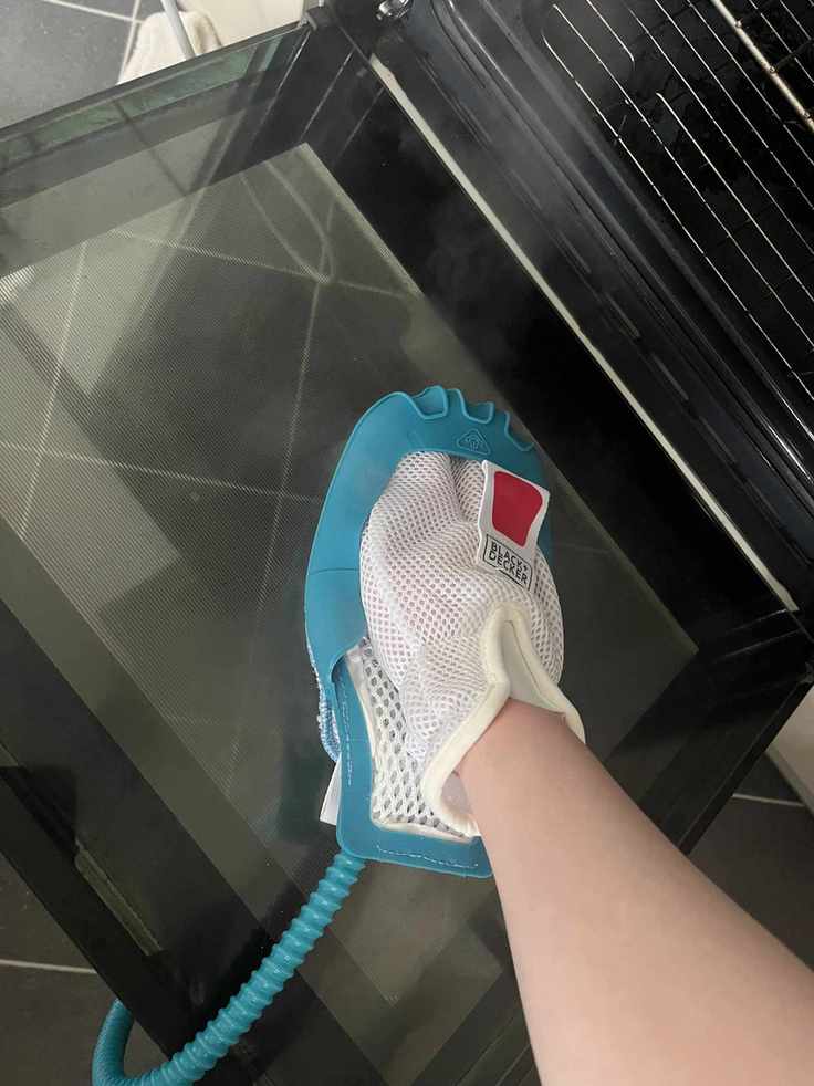 A steam cleaning mitt being used to clean a glass oven door