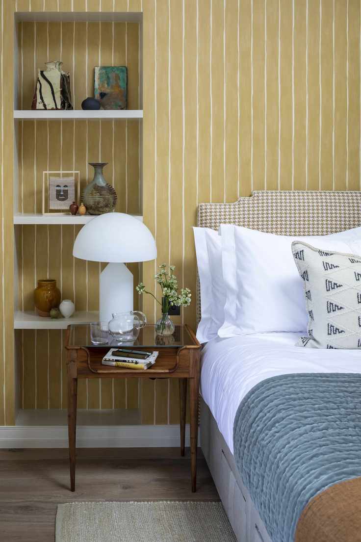 Bedroom with yellow stripe walls, white bedding, and blue throw