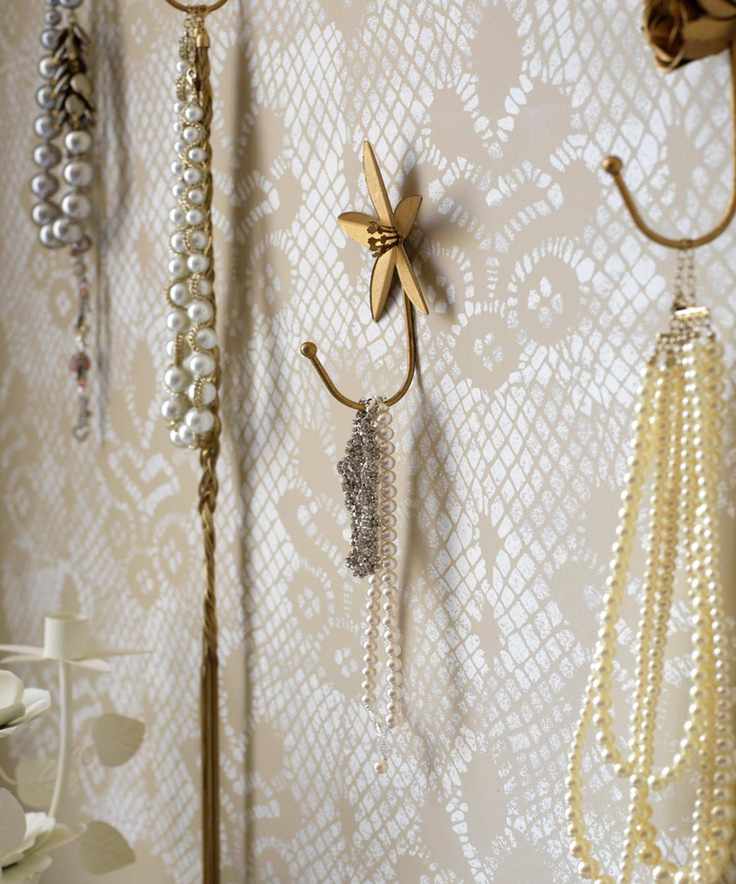 Wall with lace look wallpaper, gold hooks and pearl jewelry