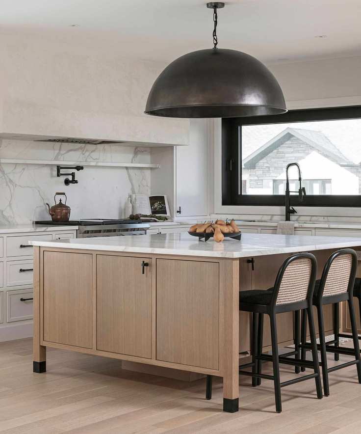 A modern kitchen with marble counters and a large bronze domed light fixture