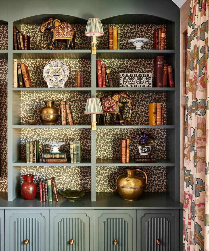 Bookshelves with light green paint and decorative wallpaper behind.