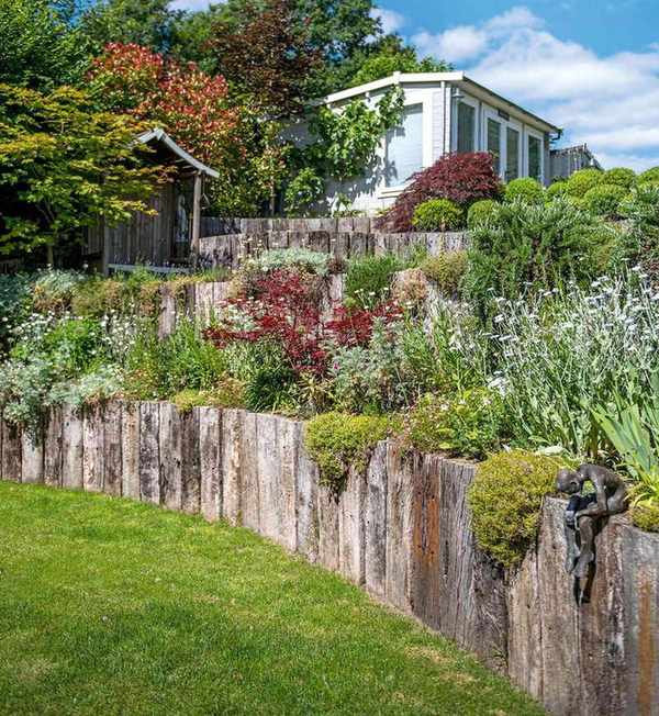 A terraced planting area with rustic wood layers and rockery style planting.