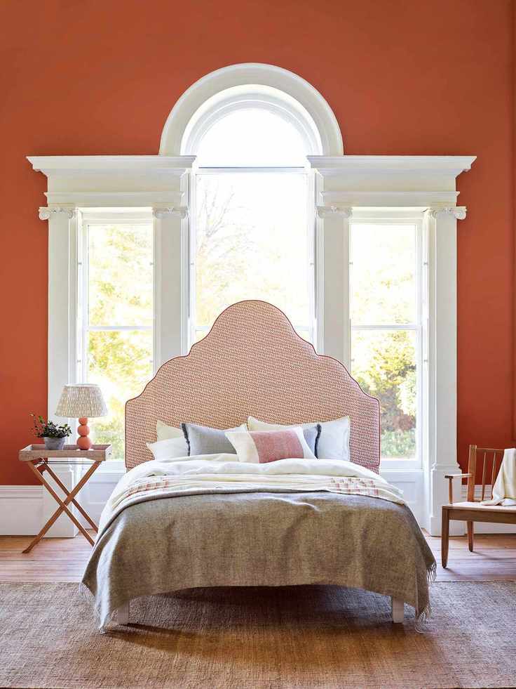 Bedroom with terracotta painted walls in Burnt Sienna and Clemmie headboard from a decor brand