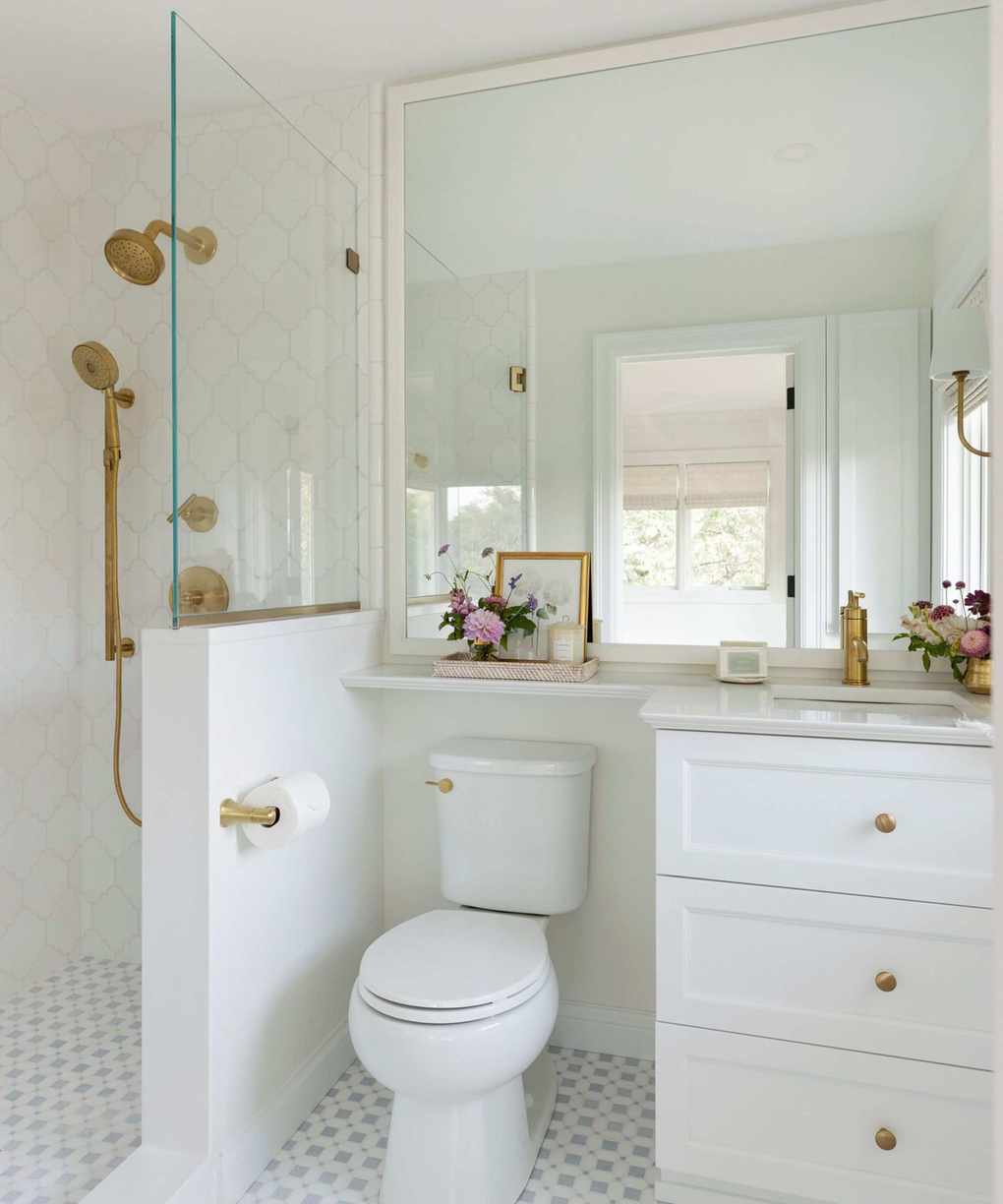 A guest bathroom with white walls and brass hardware