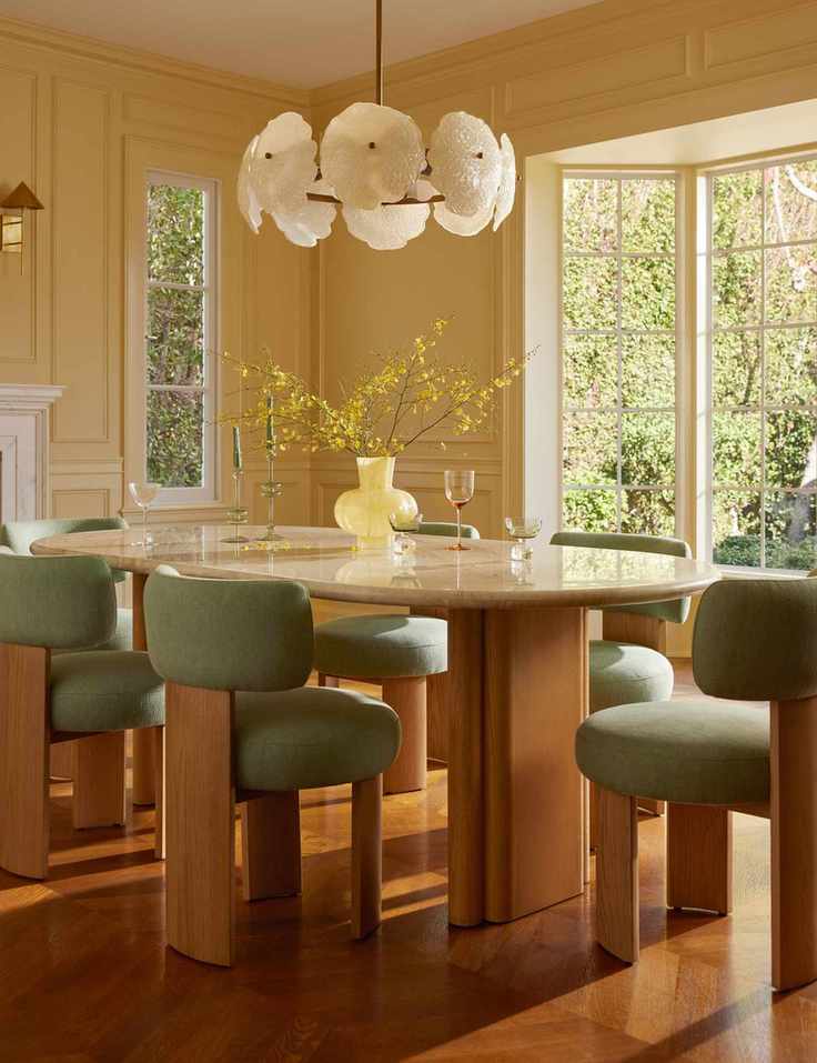 Sunny butter yellow dining room styled with sculptural mid-century furniture and a floral chandelier