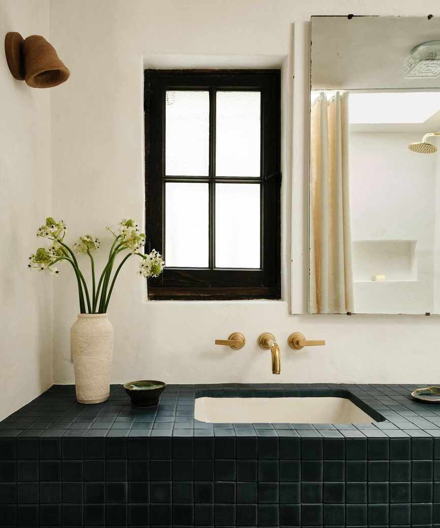 An adobe bathroom with a tiles vanity, plaster walls, and a medicine cabinet on the wall