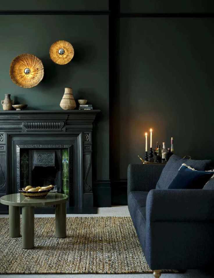 Moody dark colored living room with dark blue sofa, green shiny coffee table, gold wall art and fireplace