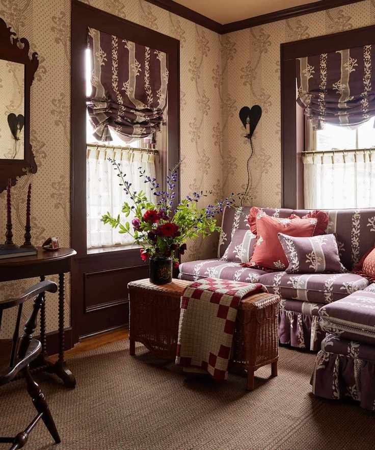 floral purple living room set up at the six bells inn hotel with a rattan ottoman with a quilt and a cozy floral banquette skirted couch