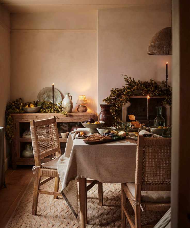 A neutral dining room decorated for fall, with garlands draped over the mantle and sideboard.