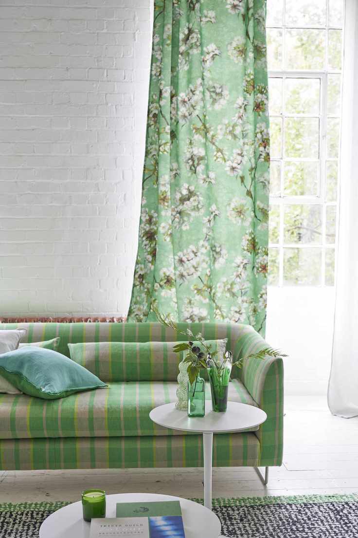 white and green living room with green floral drape, green check couch, side table, black and green rug