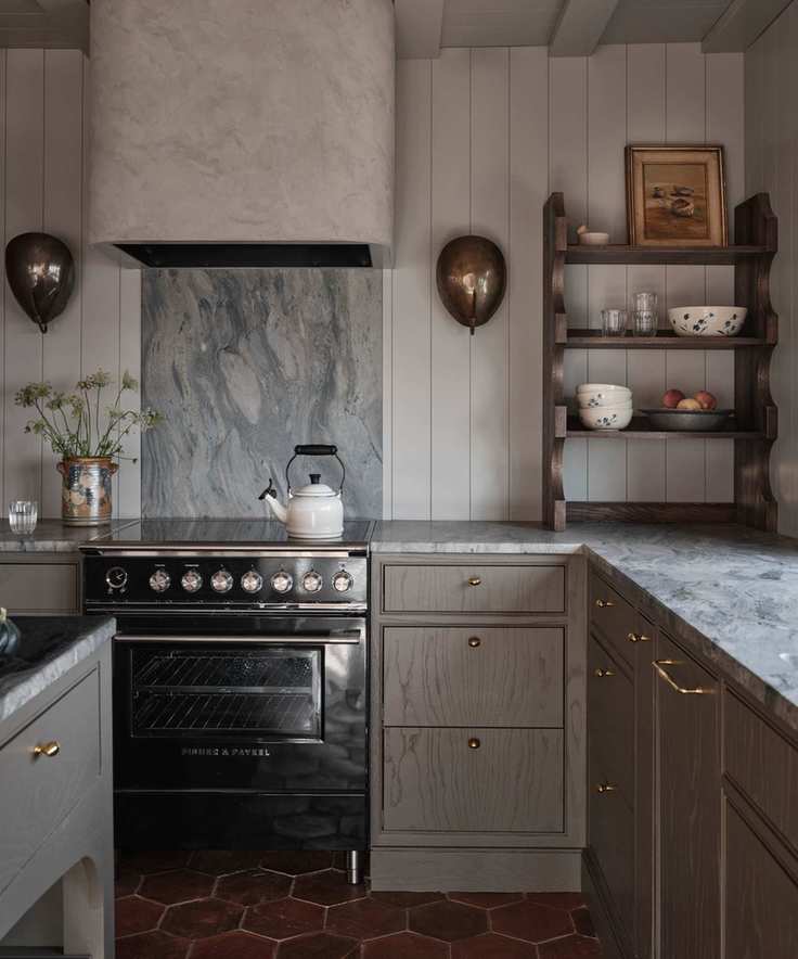 an earthy brown grey small kitchen with blue veined marble countertops and terracotta floor tiles