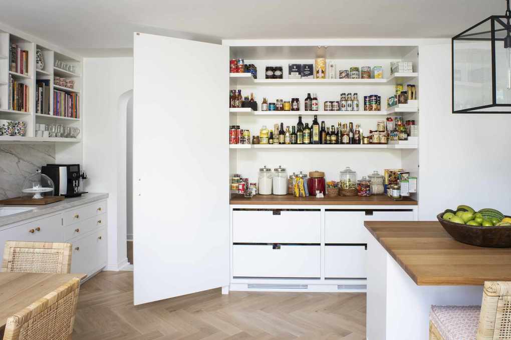 white kitchen featuring a large custom larder with visible shelving and drawers, open doors, kitchen island and cabinets, herringbone flooring