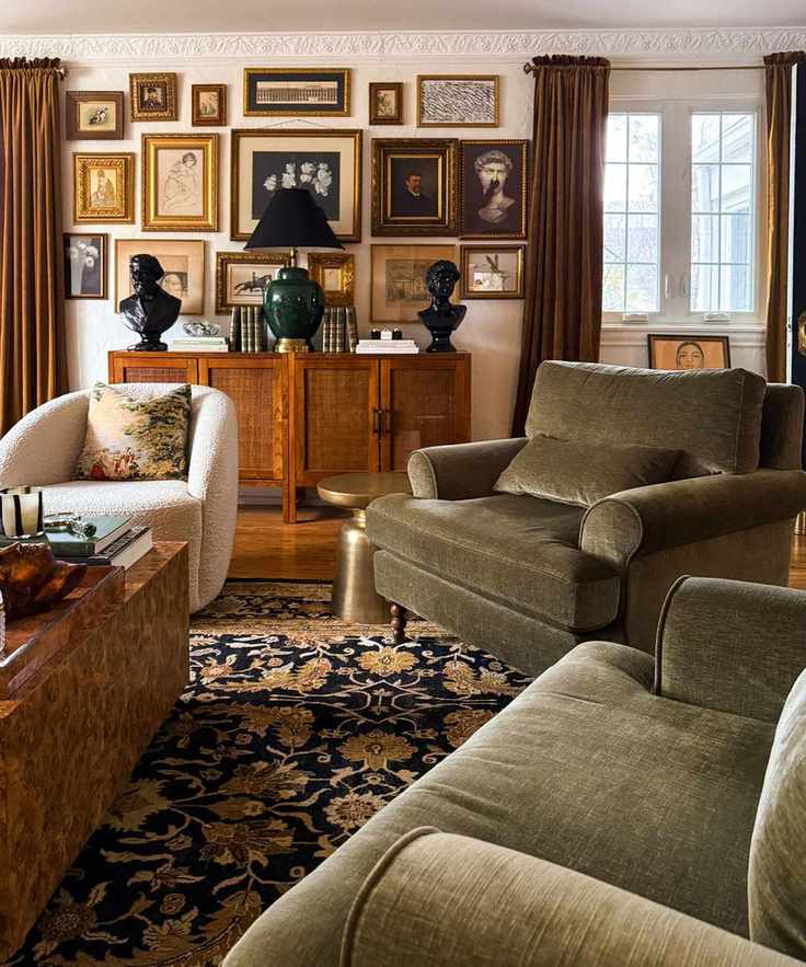 Antique living room with green velvet armchairs, floral carpet, wooden console with lots of antique paintings on wall