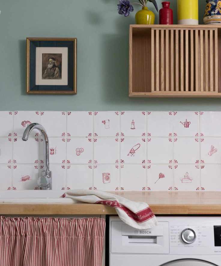 Quaint laundry room with white and red patterned tile backsplash and a white washing machine