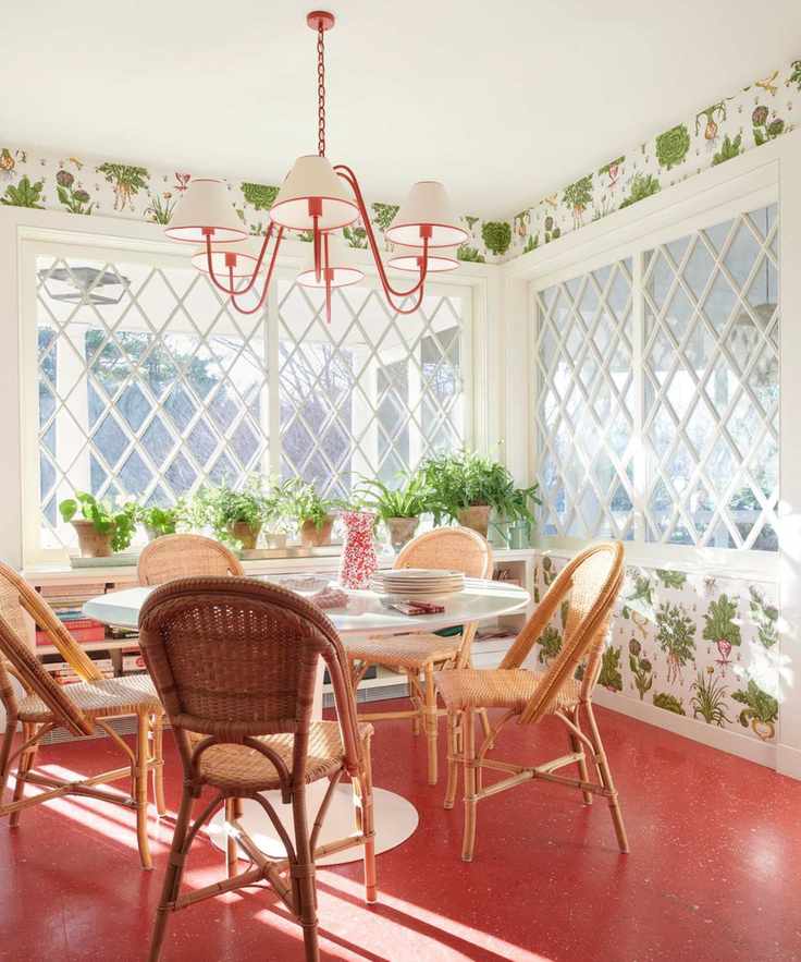 Breakfast nook with round table and rattan dining chairs and red floors, radish wallpaper and a red and white pendant light