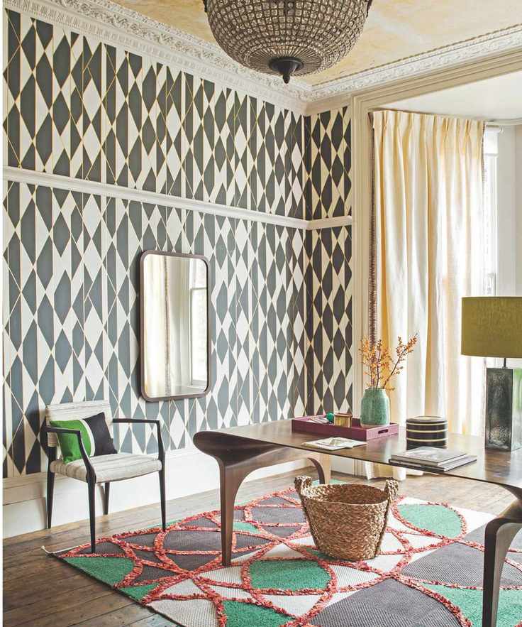 Patterned black and white wallpaper with chandelier and vibrant rug and desk