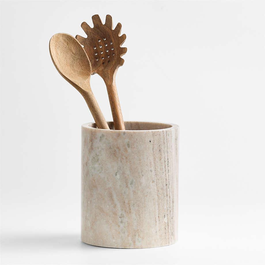 A marble utensil pot with two wooden spoons inside