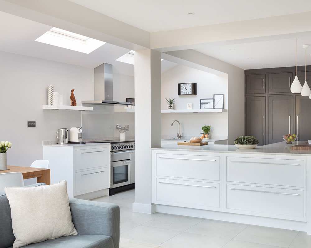 A white kitchen extension featuring skylights and a cozy sofa area