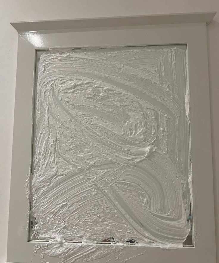 A mirror covered in shaving foam with a white wooden border