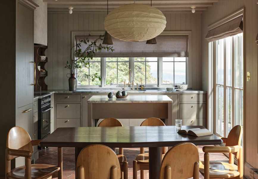 a warm stone kitchen in a lakeside cabin with a dining area and paper pendant