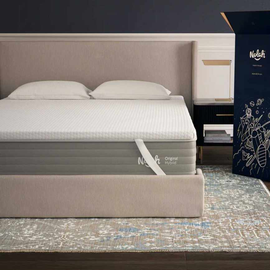 A white Nolah AirFoam® Luxe Mattress Topper on a beige bed with beige headboard, on a Persian-style rug.