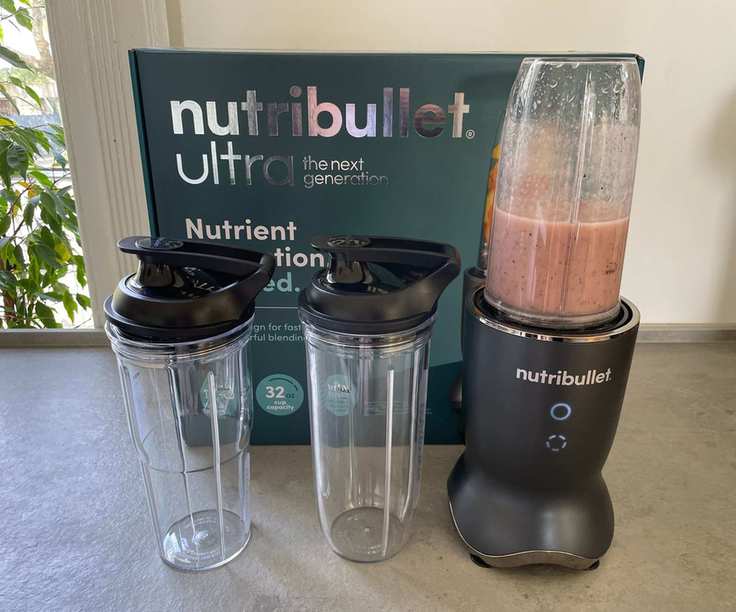 Nutribullet Ultra blender with a cup of smoothie and the two blending drinks in front of the box