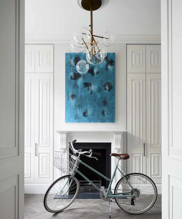 A hallway featuring white walls, a painting, and a stylish chandelier