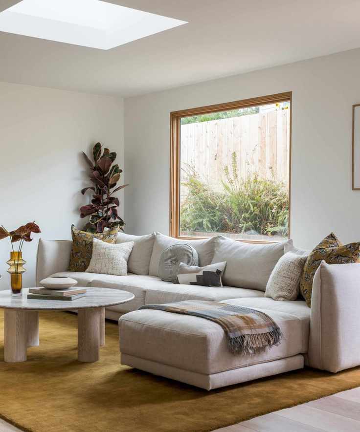 A living room with a sectional and an olive green rug