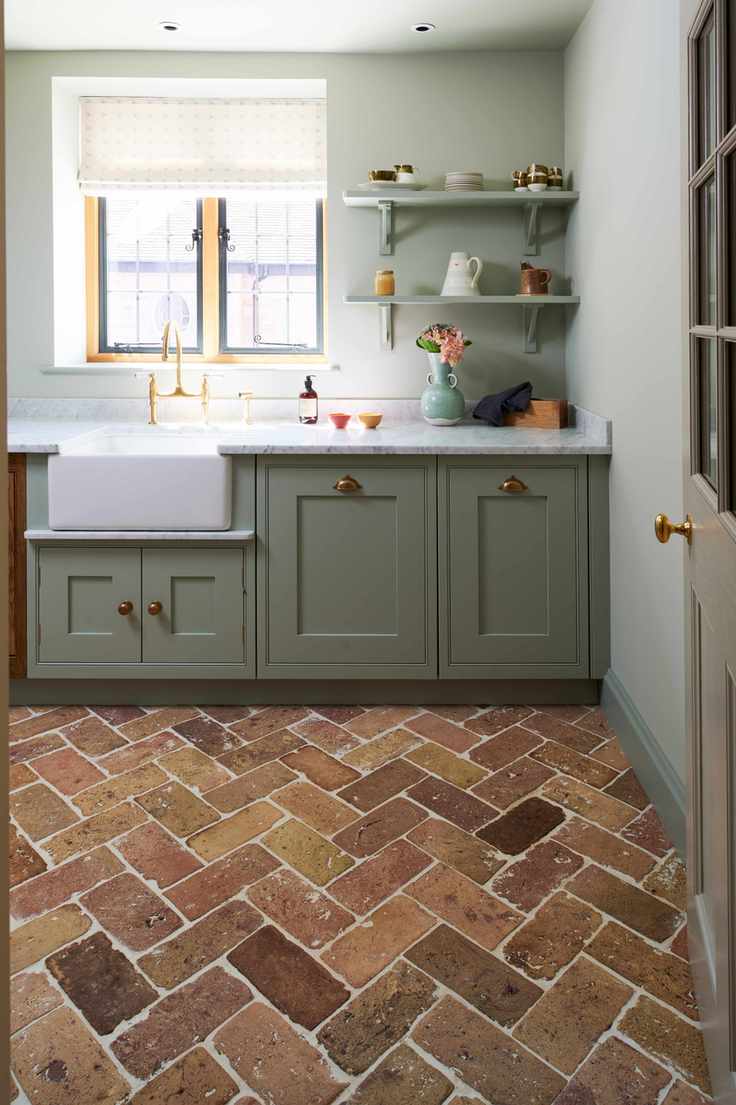 A utility room with green cabinets and a red brick floor