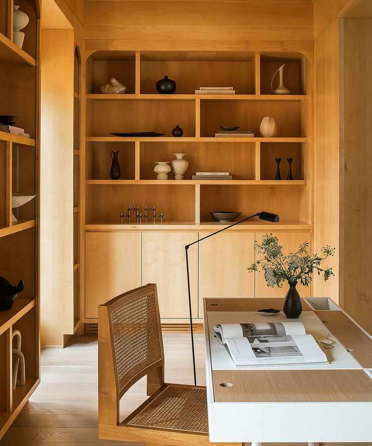 Wood office with wood shelving, midcentury wood chair and desk and lots of rustic vases