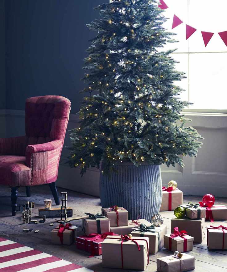 Real Christmas tree in a steel bucket with wrapped presents in front of it