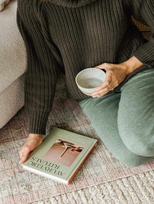 Person holding a coffee cup and a book